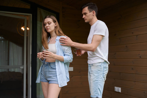 Man holding woman shoulder while standing on terrace of cottage house - Photo, Image