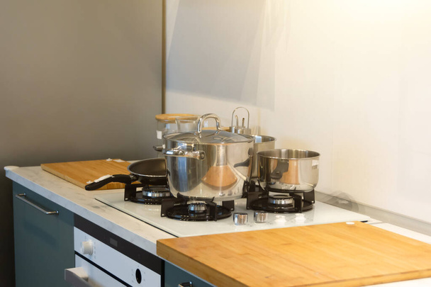 Kiiltävä keittokattila ja paistinpannuja liesi puinen pöytä valo keittiö - Valokuva, kuva
