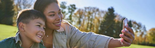 legame e amore, madre afroamericana che si fa selfie con figlio, donna e ragazzo, autunno, striscione - Foto, immagini