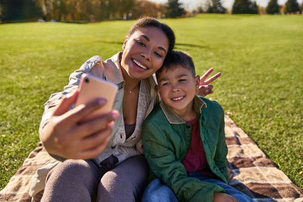 liimaus, onnellinen afrikkalainen amerikkalainen äiti ottaa selfie pojan, naisen ja pojan kanssa, syksy, v merkki - Valokuva, kuva