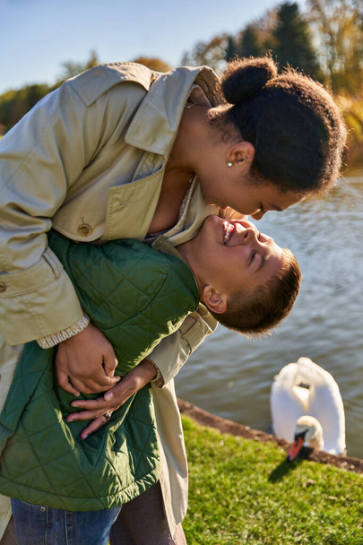 family bond, love, happy african american mother and child hugging near lake, nature, autumn, fun - Φωτογραφία, εικόνα