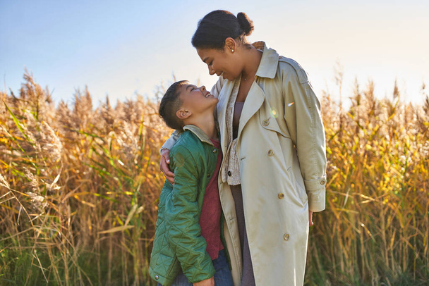 amour maternel, mère afro-américaine en vêtements automnaux embrassant son fils, saison d'automne, vêtements de dessus - Photo, image