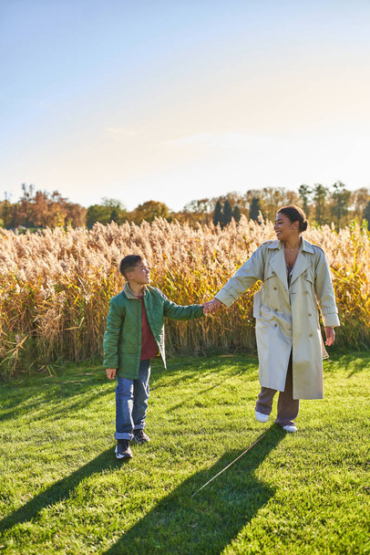 mother and son bonding, holding hands, walking in field, togetherness, motherly love concept, autumn - Foto, imagen