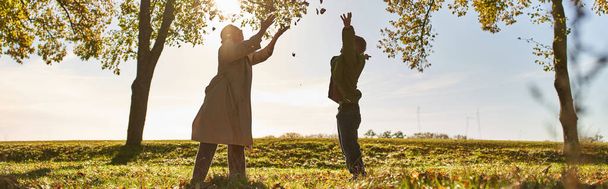 silueta de la madre y el niño lanzando hojas de otoño, parque, temporada de otoño, divertirse, bandera - Foto, Imagen