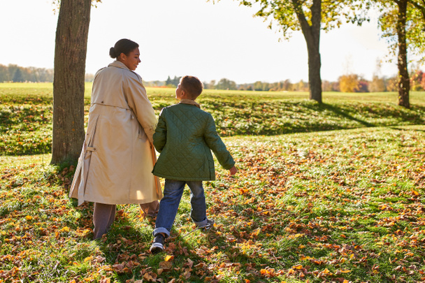 kultainen tunti, äiti ja poika kävelemässä puistossa, syksyn lehdet, syyskausi, afrikkalainen amerikkalainen perhe - Valokuva, kuva