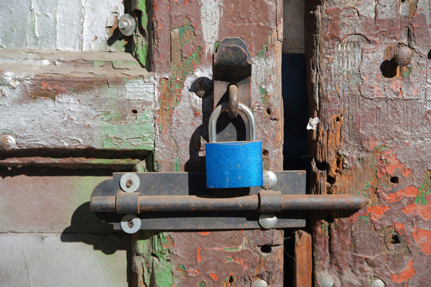Nova fechadura azul na velha porta rachada de madeira
 - Foto, Imagem