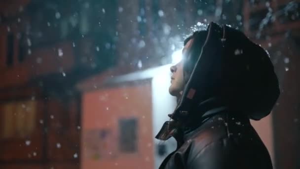 孤独な女の子がランタンが点灯する冬の通りに立って,落下する雪片を見ます. スノーウィング。 孤独の悲しみ。 4kフォーマットで高品質の撮影 - 映像、動画