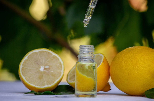 citrónový esenciální olej a citrónové ovoce na dřevěné bílé desce. Selektivní zaměření - Fotografie, Obrázek