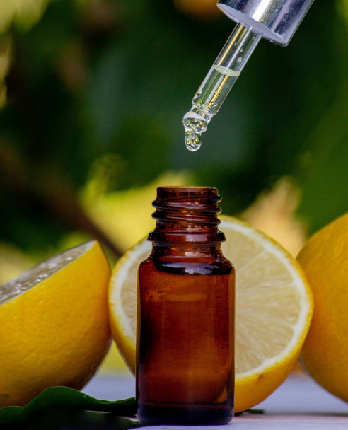 Tahta bir tahtanın üzerinde limon yağı ve limon meyvesi. Seçici odak - Fotoğraf, Görsel
