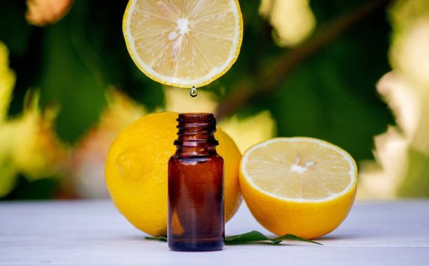 citrónový esenciální olej a citrónové ovoce na dřevěné bílé desce. Selektivní zaměření - Fotografie, Obrázek