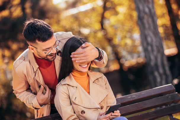 Novio sorprendiendo a su novia en un parque en un día soleado de otoño - Foto, Imagen