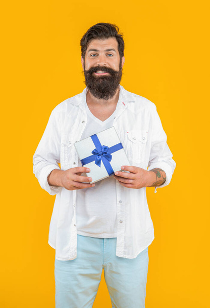 happy bearded man offer sale gift isolated on yellow. man offer sale gift in studio. man offer sale gift on background. photo of man offer sale gift box. - Foto, Imagen