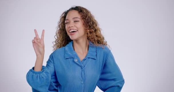 Woman, face and peace sign in studio with a smile from laughing and v hand gesture. Grey background, comic and female person with portrait and excited with casual fashion and happy emoji hands. - Footage, Video