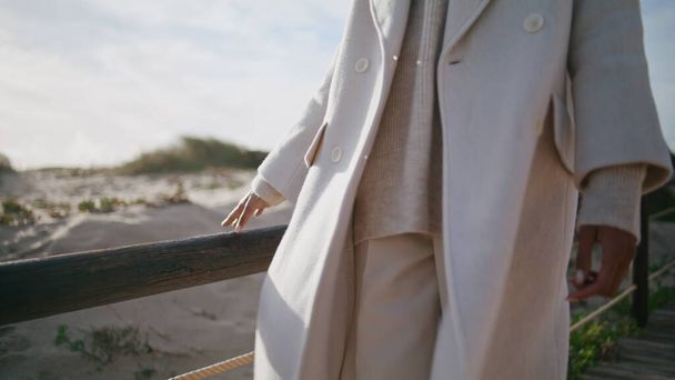 Closeup girl body strolling wooden pier. Calm serene woman touching railings enjoying sunny weekend. Unrecognized african american businesswoman taking break relaxing beach. Peaceful morning concept - Foto, Imagem
