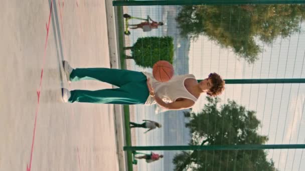 Sportovní muž praktikující pouliční basketbal sám vertikálně pohled. Soustředěný afro účes chlap, který se snaží skórovat gól na stadionu. Seriózní streetball hráč trénink venkovní na městském hřišti. - Záběry, video