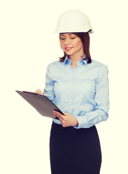 Smiling businesswoman in helmet with clipboard - Photo, Image