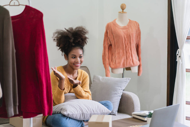 Mujer comerciante de moda afroamericana presentando y vendiendo ropa en línea en transmisión en vivo. - Foto, imagen