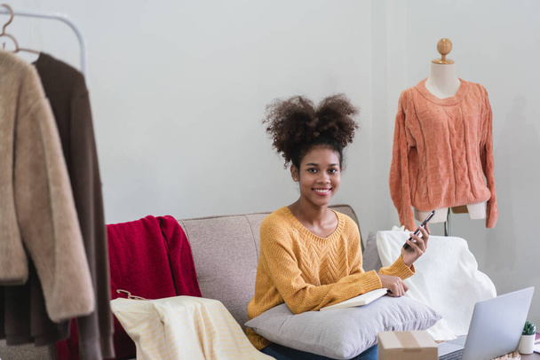 Afrykański amerykański kupiec mody kobieta pracuje z technologii sprzedaży produktów odzieżowych online. - Zdjęcie, obraz