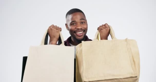 Uomo, studio ed eco friendly shopping bag con sorriso eccitato, viso o sconto da sfondo bianco. Ragazzo africano, cliente o felice per affare, vendita o risparmio con tessuto sostenibile, cura o riciclaggio. - Filmati, video