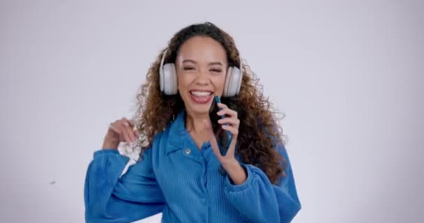 Donna felice, che canta e telefona ascoltando musica al karaoke su uno sfondo grigio da studio. Persona femminile che balla e gode di streaming audio, colonna sonora o intrattenimento radiofonico in felicità. - Filmati, video