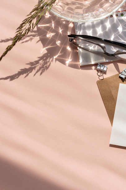 Sfondo rosa pastello vuoto con ombre astratte di luce solare, carte di carta, occhiali, flatlay femminile di business branding - Foto, immagini