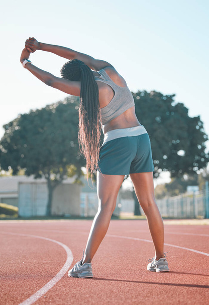 Exercise, stretching and sports woman outdoor at a stadium for workout, training and warm up. Back of athlete person for muscle stretch, fitness and wellness or flexibility for a run or competition. - Photo, Image