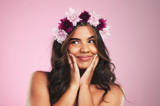 Beauty, flowers and crown on hair of woman in studio for cosmetics, skincare and wellness. Self care, spa treatment and plant with face of person on pink background for spring, glow and makeup. - Photo, Image