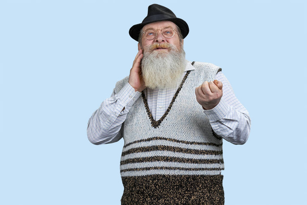 Vieil homme avec une longue barbe ayant mal à l'oreille. Isolé sur fond bleu pastel. - Photo, image