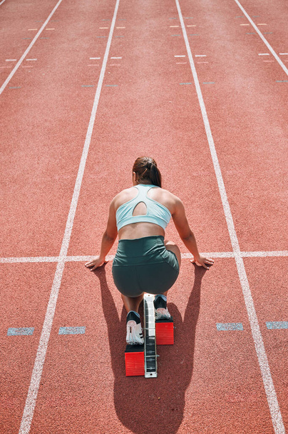 Ξεκινήστε, τρέχει και γρήγορα με τη γυναίκα στην πίστα αγώνων για τον αθλητισμό, τον ανταγωνισμό και τον μαραθώνιο. Άσκηση, υγεία και ευεξία με προπόνηση σε στάδιο για πρόκληση, ταχύτητα και ενεργειακή απόδοση. - Φωτογραφία, εικόνα