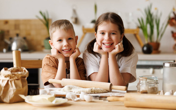 Szczęśliwe dzieci brat i siostra podejmowania ciasta podczas gotowania razem w przytulnej kuchni urządzone, uśmiechnięty chłopiec i dziewczyna mieszanie składników do domowej roboty pierniki - Zdjęcie, obraz
