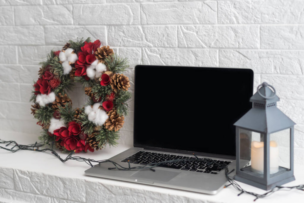 Um laptop aberto na mesa ao lado de uma árvore de Natal decorada com bolas e uma grinalda. Ano Novo e clima de Natal no local de trabalho. - Foto, Imagem