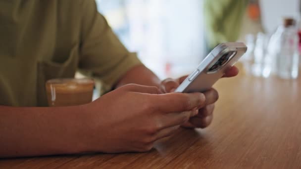 Mann gibt SMS auf Handy in Cafeteria in Großaufnahme. Unbekannter Mann mit Smartphone im Café sitzend mit Tasse aromatischem Kaffee Unbekannter verschickt SMS für Verabredung im Kaffeehaus - Filmmaterial, Video