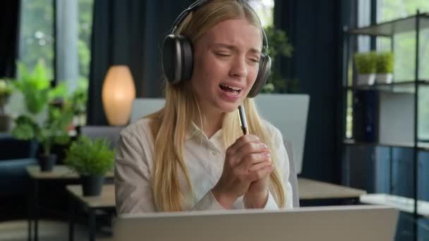 Caucasian woman business girl listen music in headphones at office workplace sing favorite song in pen like microphone female carefree funny singer businesswoman employee dance singing to laptop audio - Footage, Video