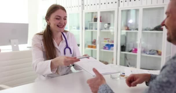 Νοσοκόμα ιατρός δίνει πρόχειρο με έγγραφα στον ασθενή για να υπογράψει για την επιτυχή δοκιμή. Αποτελέσματα δοκιμών σε ιδιωτικό νοσοκομείο ραντεβού αργή κίνηση - Πλάνα, βίντεο