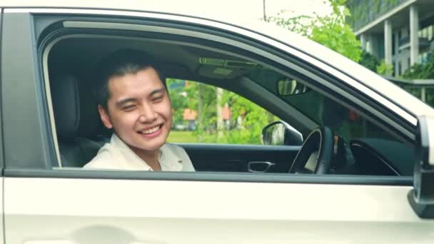 Portre yakışıklı Asyalı beyefendi araba kullanıyor. Üye sigorta kartını gösteriyor. Müşteri huzuru için arabayı kullanıyor ve sigorta poliçesiyle güvenli bir şekilde sürüyor.. - Video, Çekim