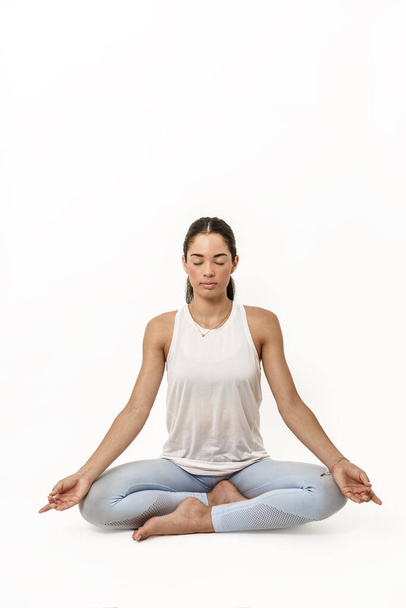 image on a white background of a woman sitting with one leg on top of the other and palms on her knees while her eyes are closed in a state of meditation. It is the padmasana, or lotus posture, the pose that is conducive to full meditation. - Photo, Image