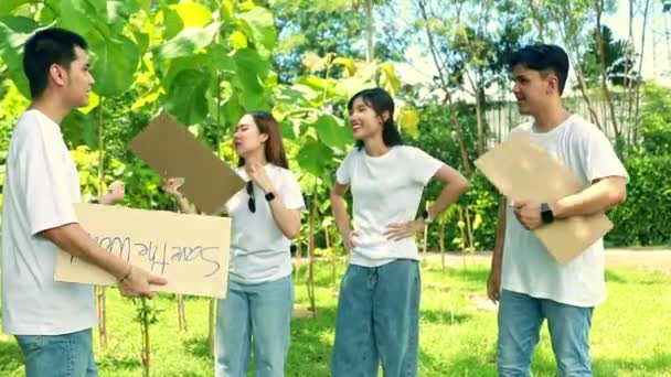 Волонтеры студентов мужского и женского пола держат в руках документы, готовящиеся к кампании по очистке зеленого лесного парка, стоят на открытом воздухе в жаркую летнюю жару. - Кадры, видео