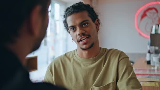 Két kolléga találkozik a kávézóban, hogy megbeszéljék a munka indítását. Latin-amerikai fiatalember beszél egy felismerhetetlen baráttal, aki együtt ül. Brazil srác hipster élvezze a barátságos kommunikációt a bárban. - Felvétel, videó