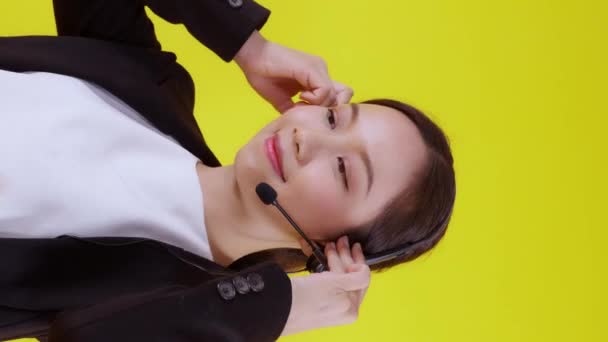 Retrato de mujer de negocios asiática joven centro de llamadas con auriculares sobre fondo amarillo, agente con apoyo y servicio, mujer de negocios es asistente para el cliente con teléfono o línea de ayuda en línea. - Imágenes, Vídeo