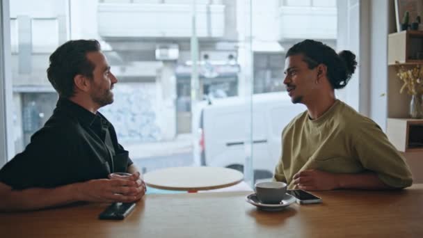 Οι άντρες κολλητοί μιλάνε σε μια μικρή καφετέρια το πρωί του Σαββατοκύριακου. Δυο πολυεθνικοί έχουν φιλική συνάντηση στην καφετέρια της πόλης. Χαρούμενοι άνδρες που μοιράζονται σκέψεις συζητώντας ειδήσεις μαζί. - Πλάνα, βίντεο