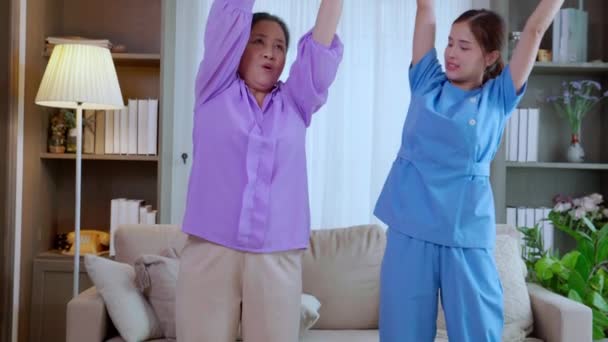 Mujer cuidadora asiática o enfermera entrenando a una mujer mayor levantando pelota deportiva con las manos para hacer ejercicio mientras fisioterapia y rehabilitación, cuidadora o fisioterapeuta ayuda a entrenar a ancianos. - Metraje, vídeo