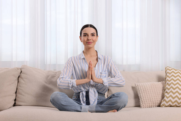 Woman meditating on sofa at home. Harmony and zen - Photo, Image
