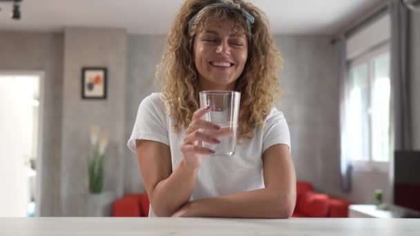 een volwassen blanke vrouw zitten thuis houden glas water gelukkig glimlach - Video