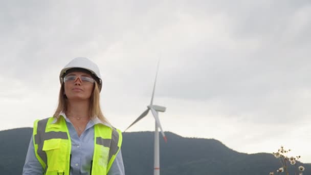 A nők véleménye a szélerőműparkokról: a tervező zöld energiájú turbinákat szervez a leghatékonyabb szélenergia-felhasználás érdekében. Egy védőmellényes és védőszemüveges mérnök részletesen tanulmányozza a szélmalmok gazdaságát, amely - Felvétel, videó