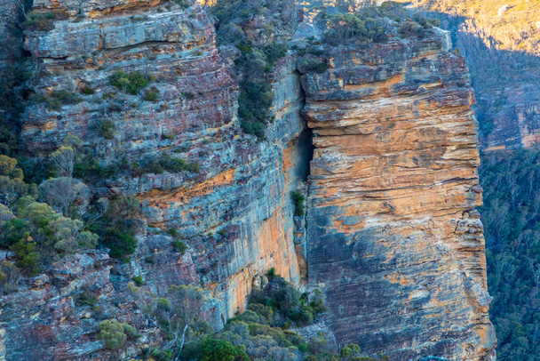 Foto van de ruwe en rotsachtige rotswand van de bergen in de Megalong Valley in de Blue Mountains in Nieuw-Zuid-Wales in Australië - Foto, afbeelding