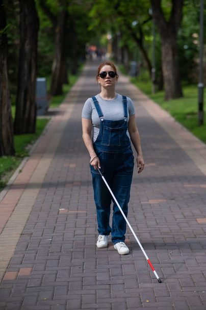 Blind pregnant woman walking in the park with a cane - Foto, Imagen