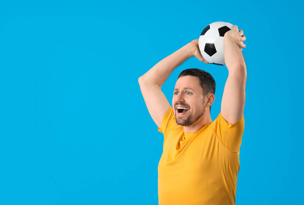 Hombre con pelota de fútbol sobre fondo azul - Foto, imagen