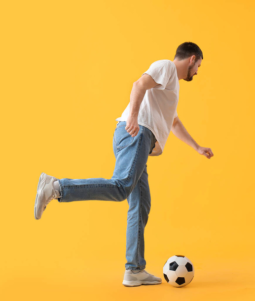 Ο άνθρωπος παίζει με μπάλα ποδοσφαίρου σε κίτρινο φόντο - Φωτογραφία, εικόνα