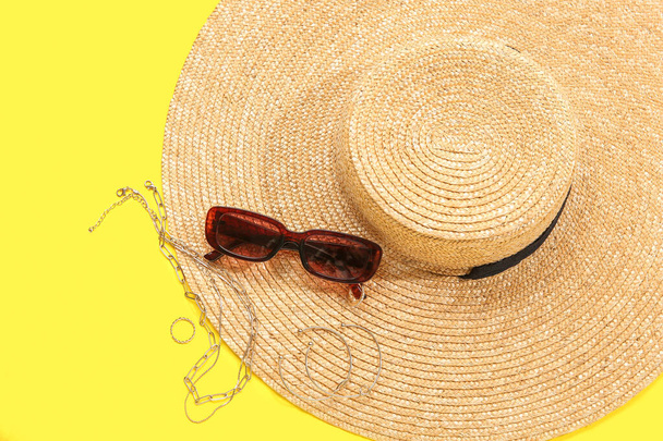 Occhiali da sole eleganti con cappello e gioielli su sfondo giallo - Foto, immagini