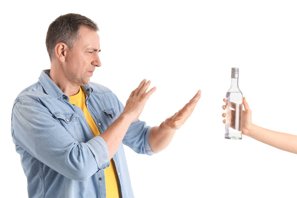 Memnun olmayan olgun bir adam beyaz arka planda votka şişesini reddediyor. - Fotoğraf, Görsel